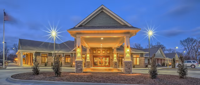 Front entrance of Stillwater Senior Living at dusk with illuminated portico.