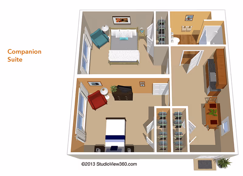 3D floor plan of a companion suite featuring two bedrooms, each with a bed, chair, and side tables. The suite includes a bathroom with a shower, a kitchen area with cabinets and appliances, and a dining table with chairs. There are closets between the bedrooms and near the bathroom.