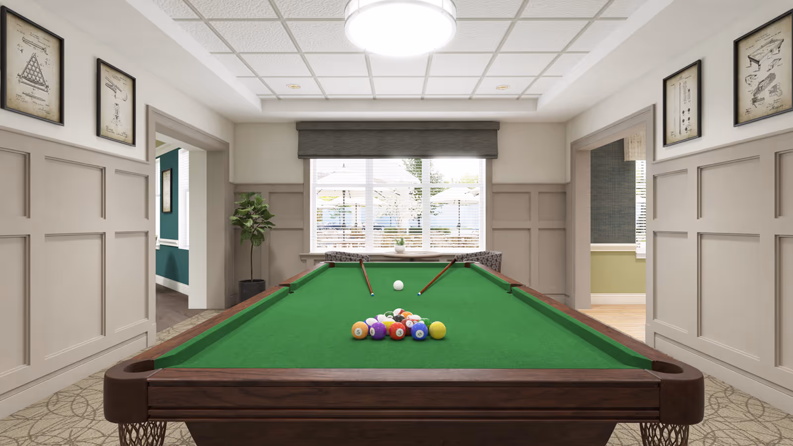 A bright interior game room featuring a pool table centered under a ceiling light with cue sticks and racked balls and a window at the far wall.