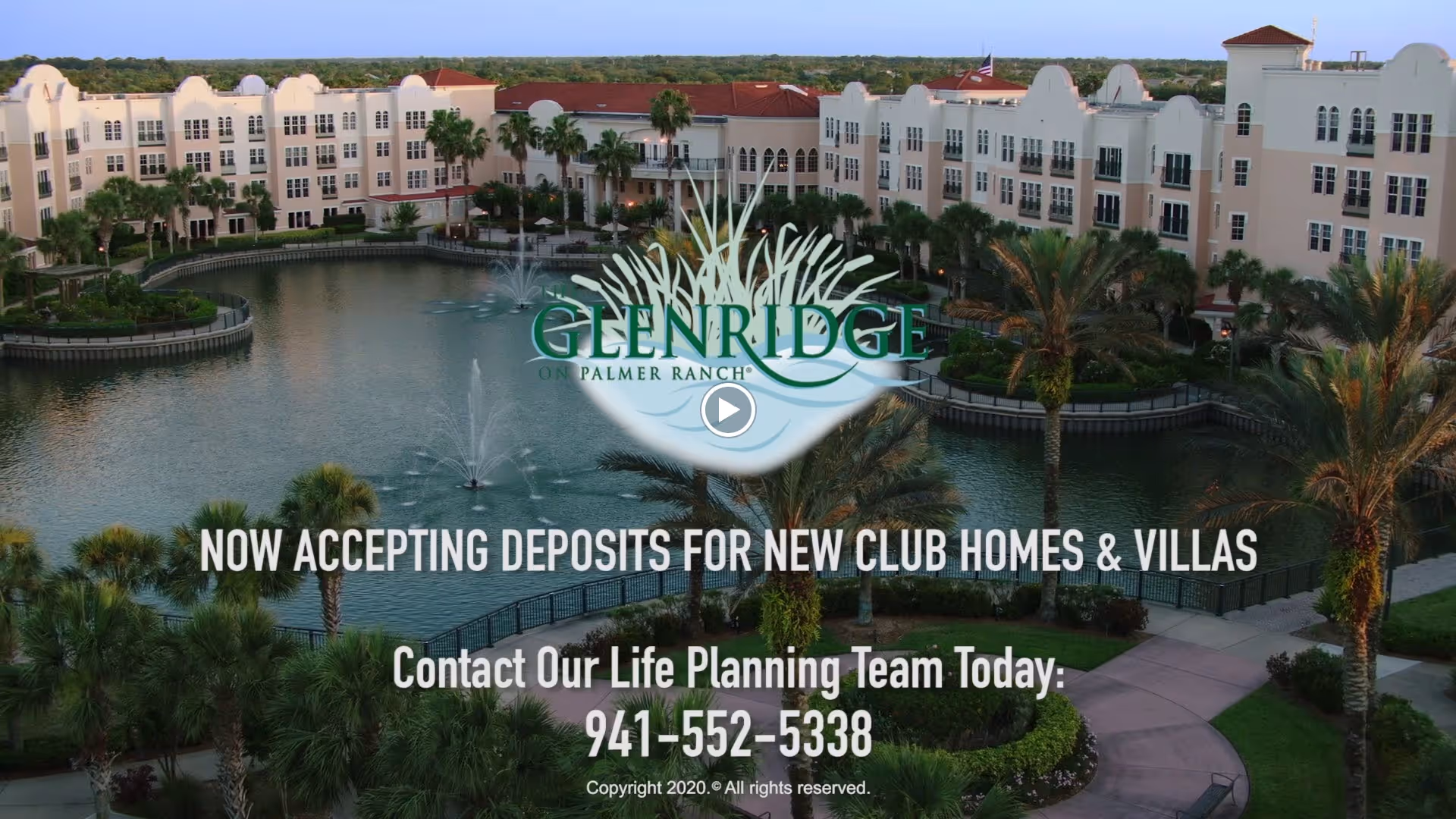 A large senior living facility named The Glenridge on Palmer Ranch is shown with a central pond featuring fountains, surrounded by palm trees and landscaped walkways. The multi-story building has a light exterior with red roofs and multiple windows.