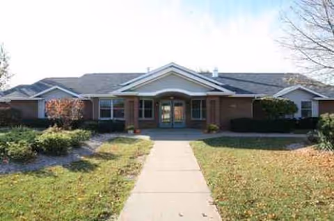 Single-story senior living facility front entrance with a walkway and trimmed lawn.