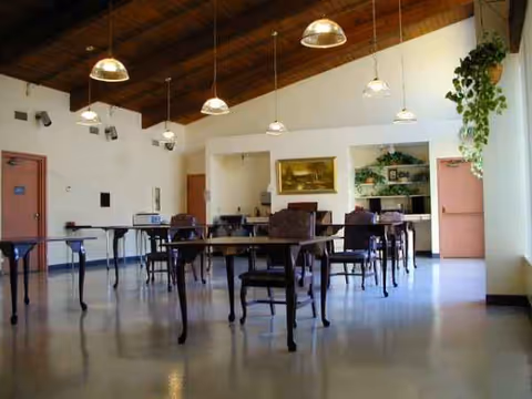 Interior dining room with tables and chairs arranged for residents in a senior facility.