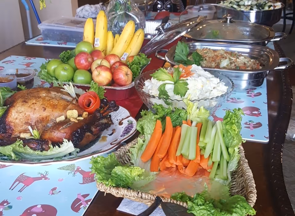 A buffet-style dining table with a roasted turkey, fresh fruit, salads, and vegetable platters.