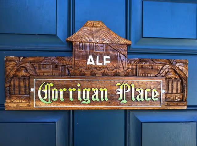Wooden Corrigan Place ALF sign mounted on a blue door