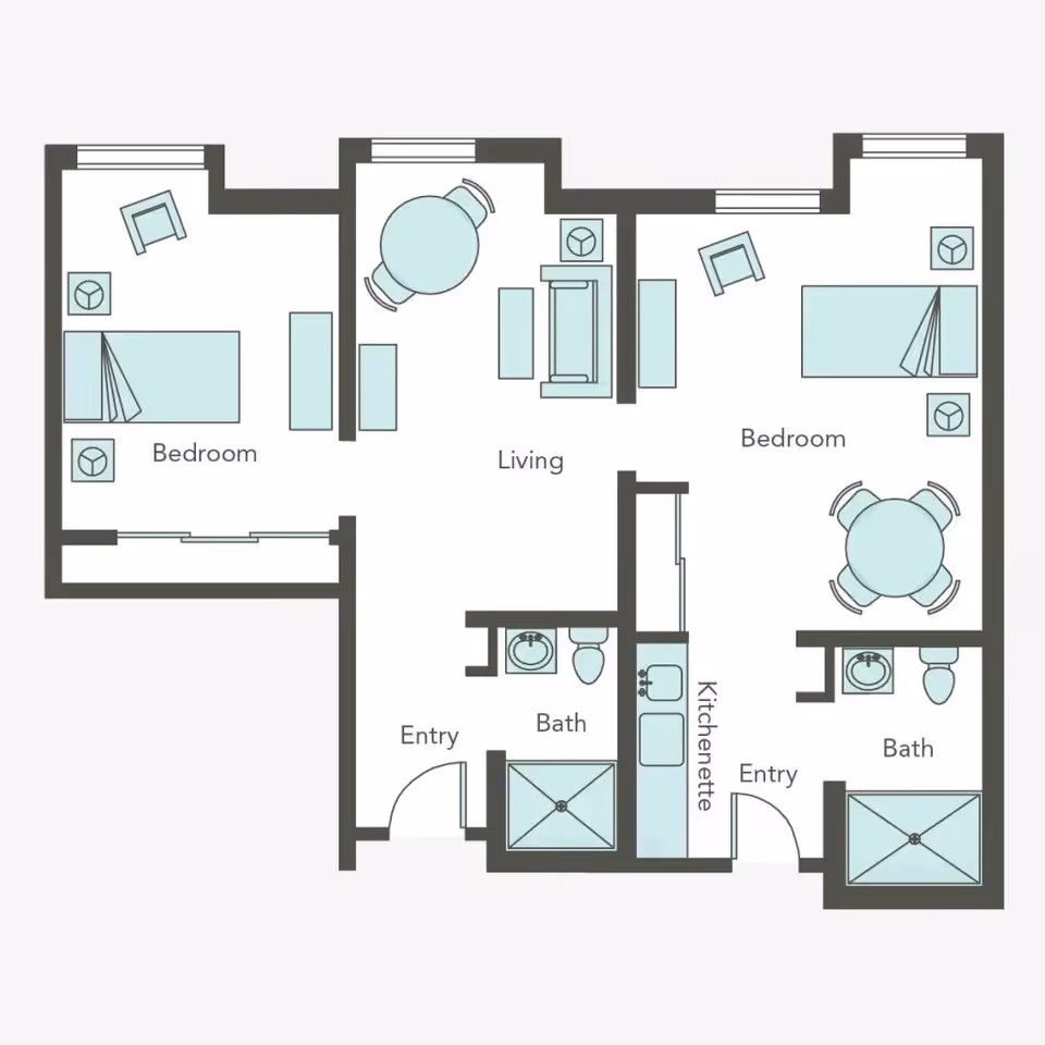 Floor plan of a living space at Aegis Lodge showing two bedrooms, a living room, two bathrooms, a kitchenette, and two entry points. Each bedroom has a bed, chair, and side tables. The living room has a sofa, coffee table, and a round dining table with chairs. Both bathrooms include a sink, toilet, and shower.