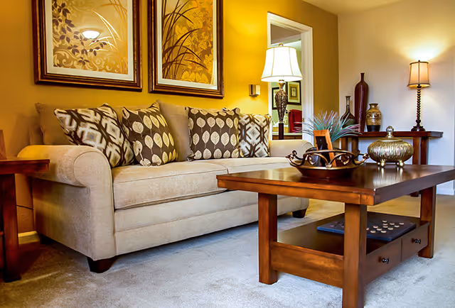 Cozy living room with a beige sofa, patterned throw pillows, a wooden coffee table and decorative lamps.