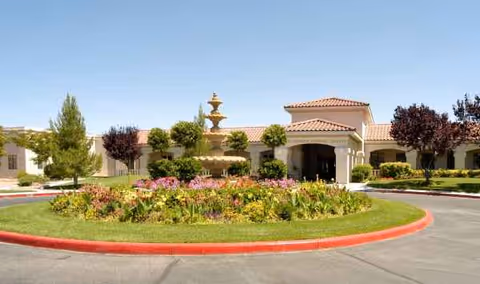 Sunny exterior view of Oasis Nursing & Rehab of Green Valley featuring a fountain and garden.