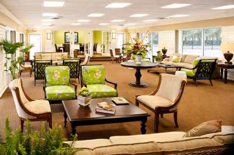 Spacious indoor lounge with sofas, chairs, tables, plants, and large windows.