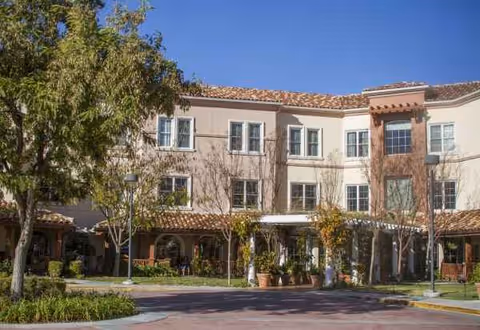 Sunrise of Westlake Village building exterior with arched entryways and potted plants.