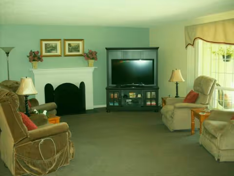 Cozy living room with fireplace, TV, lamps, and comfortable seating.