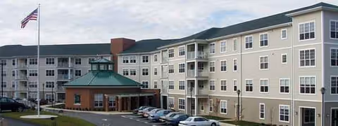 Exterior view of Redstone Highlands senior living building with cars and flag.