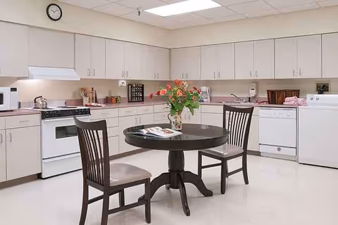 Clean communal kitchen in a senior facility with a round table and two chairs.