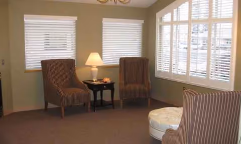 Cozy living room at Regency at Northpointe with striped chairs, lamp, and large windows.