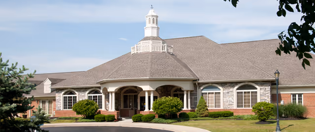 Front exterior of the Gardens of Scioto senior living building with a covered entrance, cupola, and landscaped grounds.