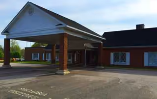 Front entrance of a brick nursing home with a covered drop-off area.