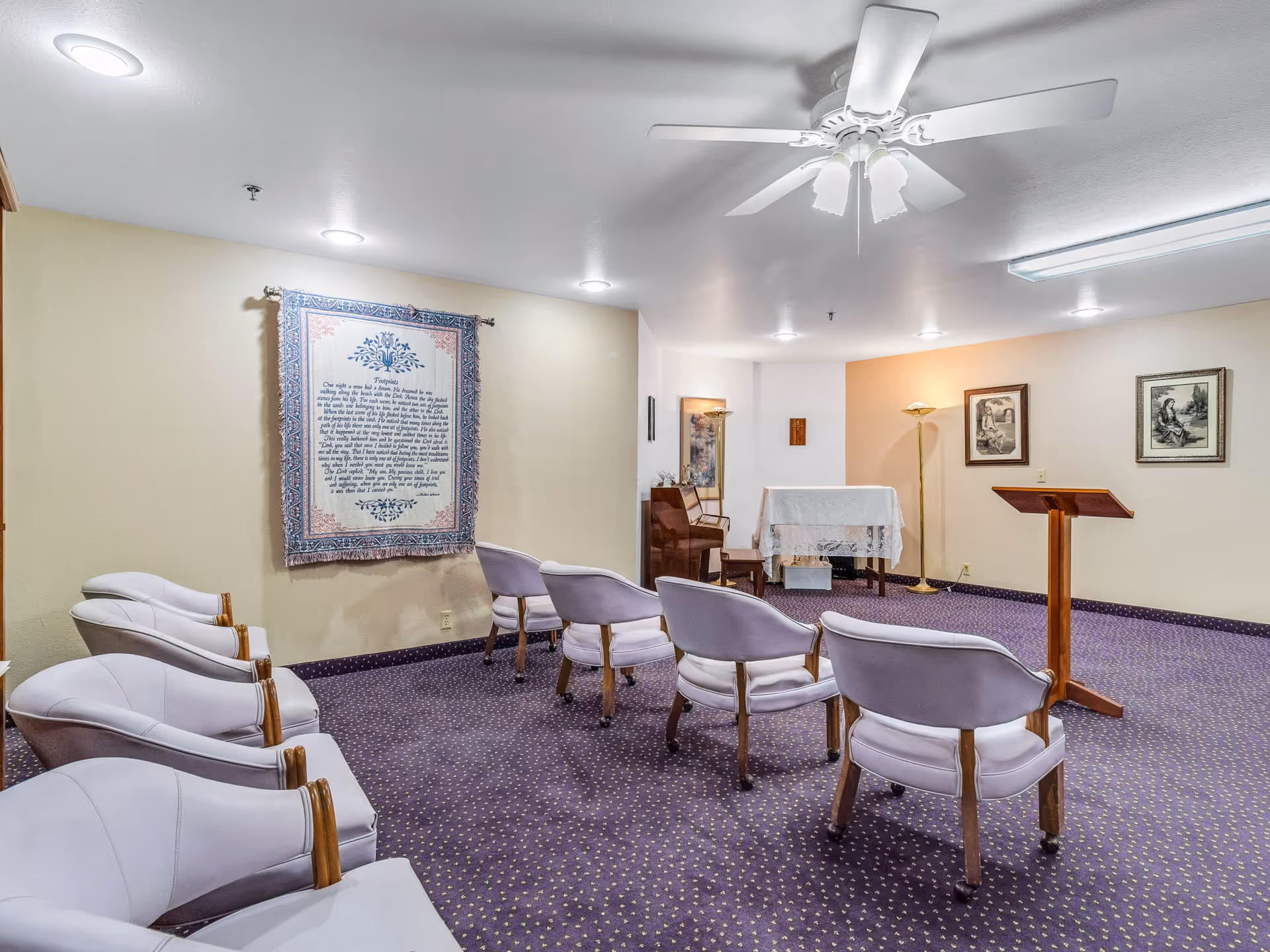 Small chapel-style meeting room with upholstered chairs arranged facing a lectern and a small altar table.