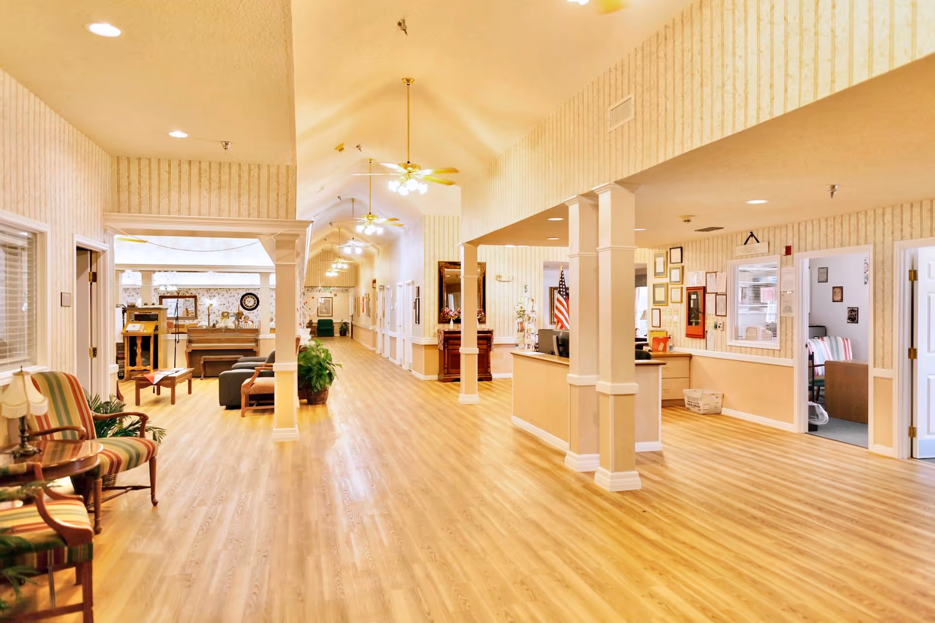 Bright, spacious interior hallway and common sitting area with wood floors, seating, and a reception desk.