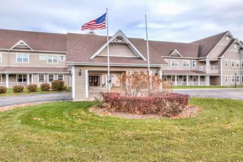 Front exterior of Grand Victorian of Sycamore, a senior living facility with flag.