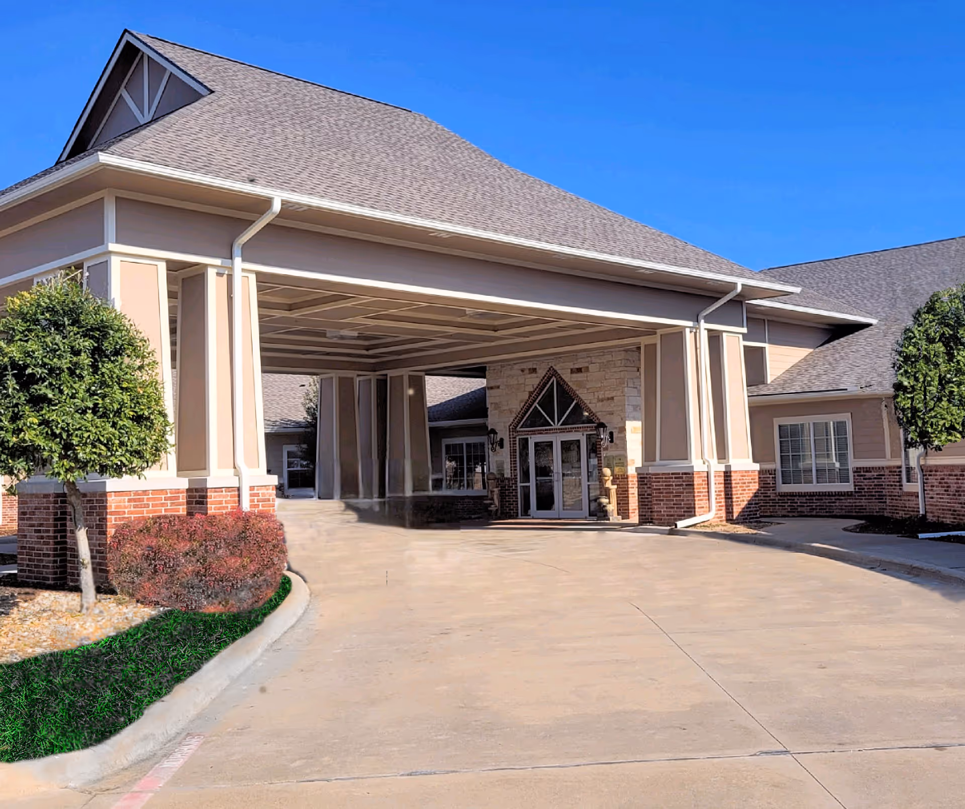 Exterior view of Autumn Wind Assisted Living entrance with a covered driveway and landscaping.