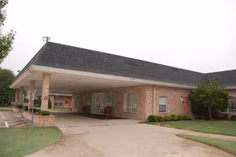 Brick senior living facility with a covered entrance and landscaped front yard.