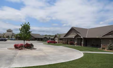 Exterior view of Reflection Living facility with curved driveway, lawn, and parked car