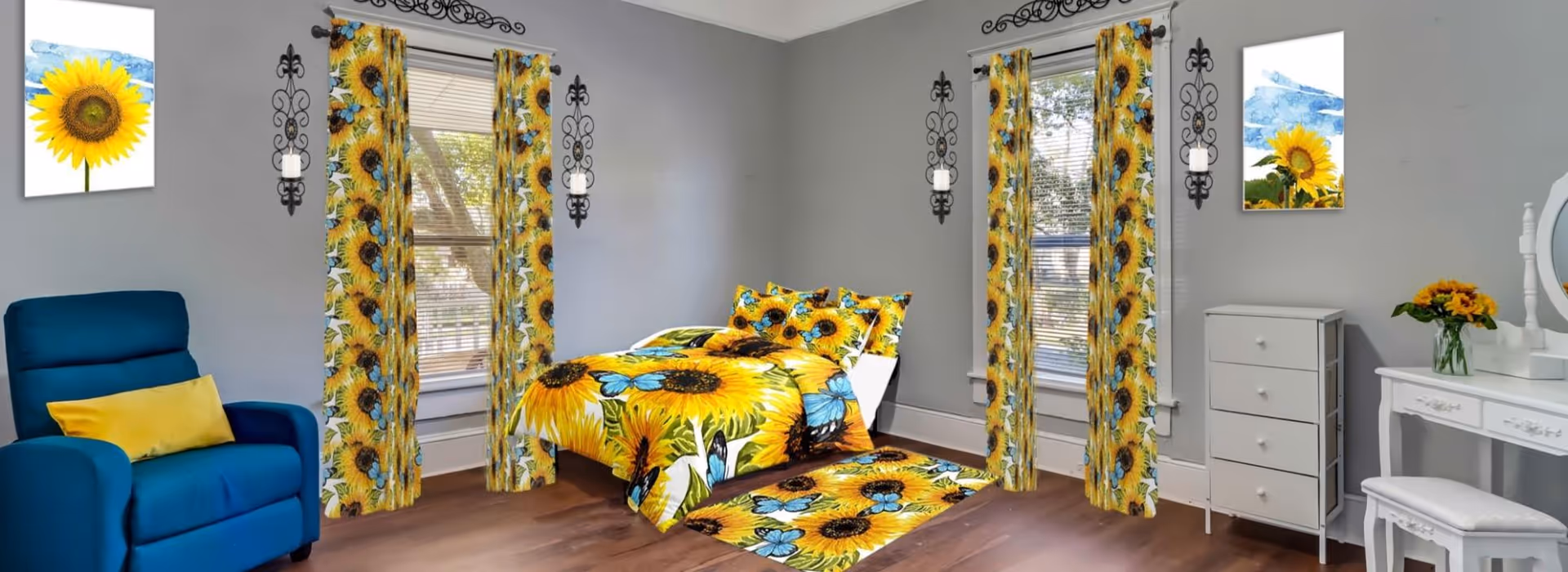 A bright bedroom with sunflower and blue butterfly themed decor including curtains, bedding, and a rug. The room features a blue armchair with a yellow pillow, two windows with blinds, sunflower artwork on the walls, a white dresser, and a white vanity with a matching stool and a vase of sunflowers.
