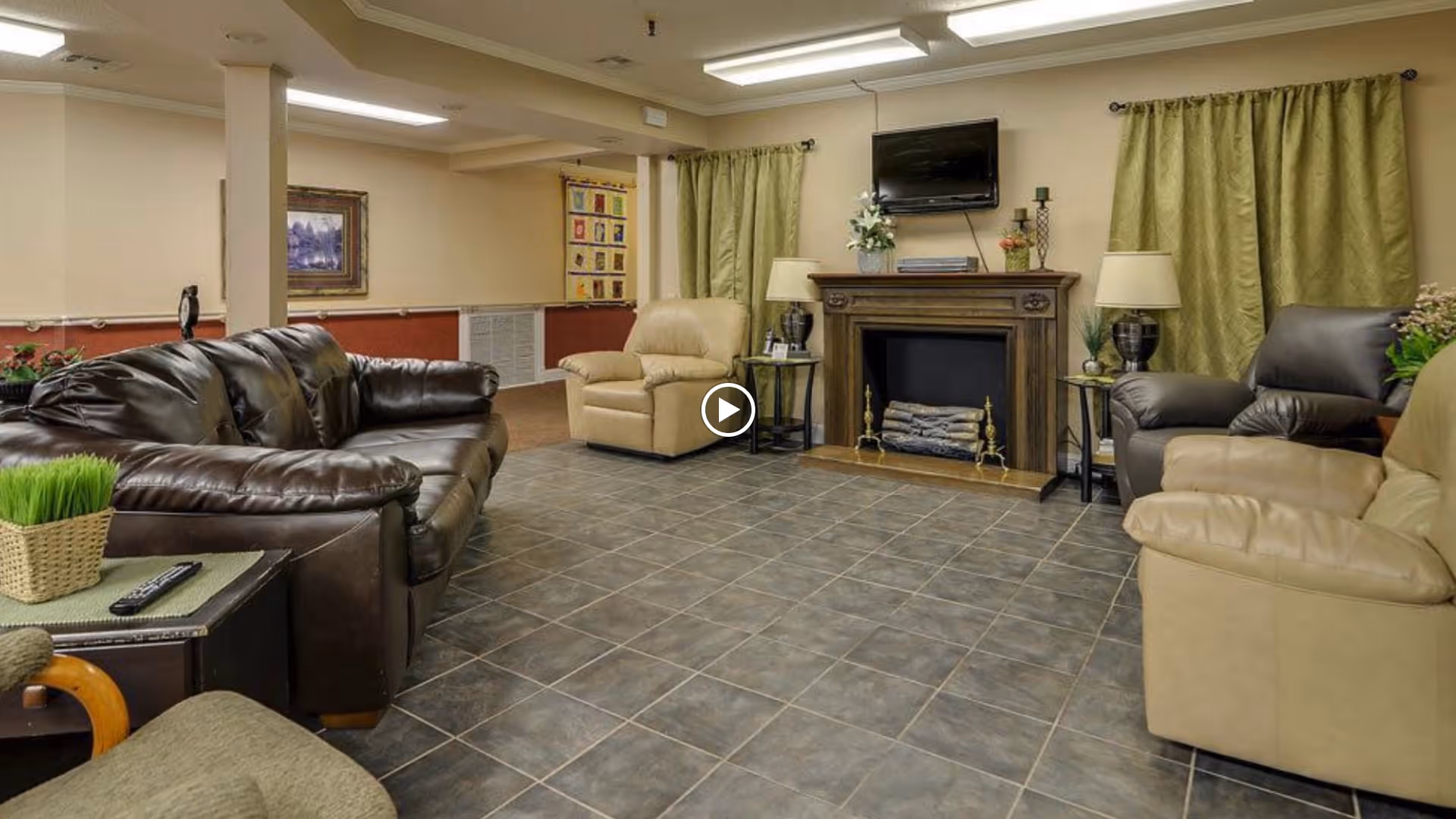 A lounge with leather sofas and armchairs arranged around a decorative fireplace and wall-mounted TV.