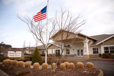 Front view of Rosewood Memory Care facility with American flag, entrance, and rounded landscaping.