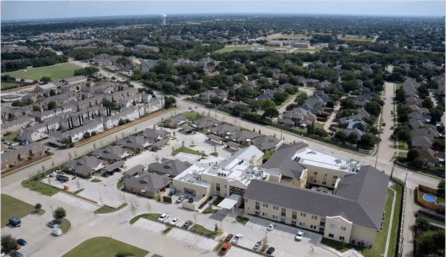 Aerial view of a senior living facility surrounded by residential neighborhoods. The facility has multiple connected buildings with parking lots and landscaped areas.
