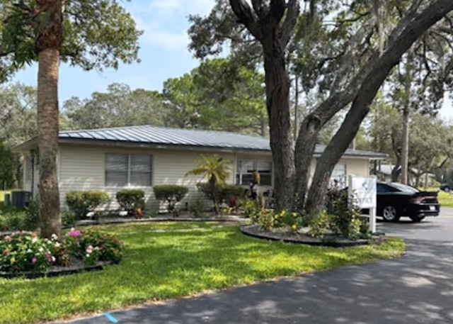 Front view of a senior living facility with landscaping and a parked car