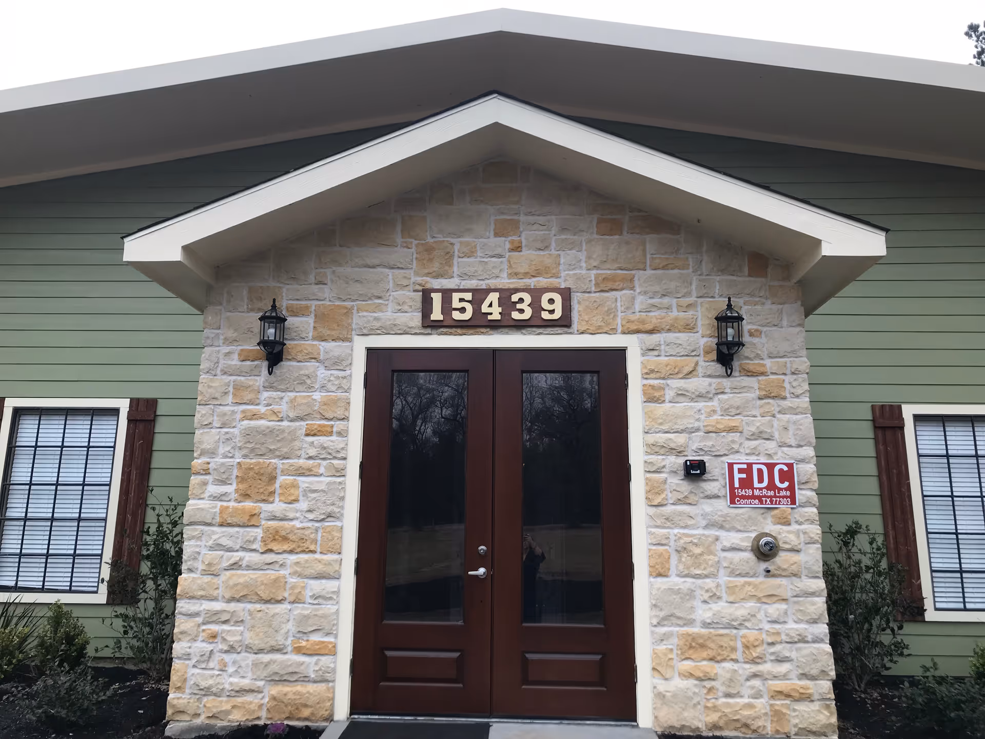 Front entrance of a building with a stone facade, double glass doors, and the address '15439' displayed above.