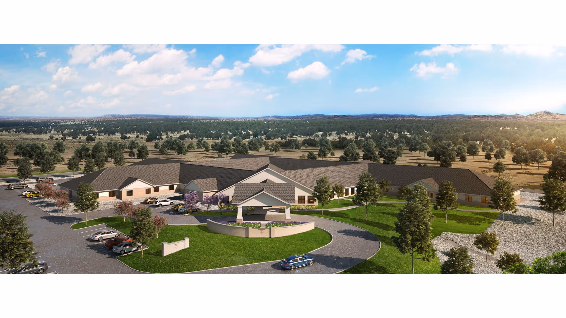 Aerial view of Las Alturas Nursing & Transitional Care facility showing a large single-story building with a circular driveway and landscaped green areas. Several cars are parked in the parking lot surrounding the building. The facility is situated in a rural area with many trees and open land extending to the horizon under a partly cloudy blue sky.
