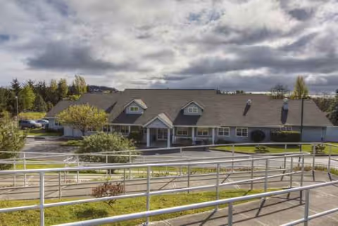 Exterior view of Victoria Place Senior Living building with ramp and parking.