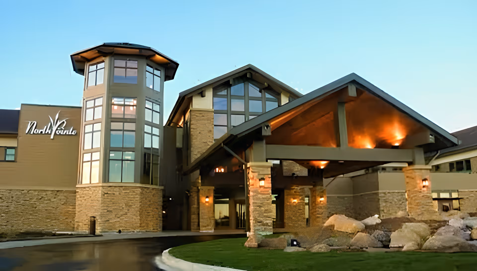 Front entrance of the NorthPointe Terrace building with a covered porte-cochere, stone facade, and illuminated tower windows.
