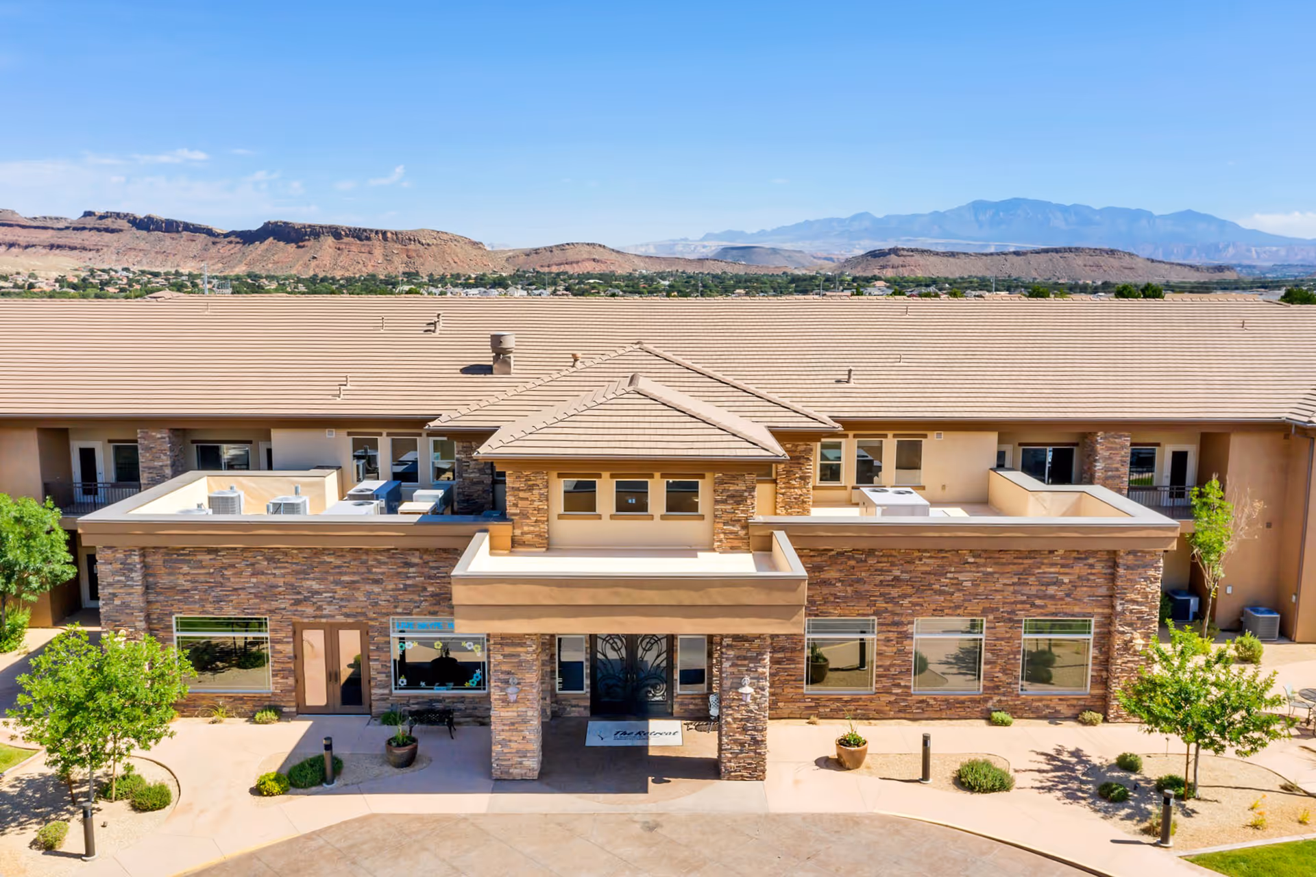Front exterior of a stone-clad senior living facility with desert landscaping and mountain backdrop.