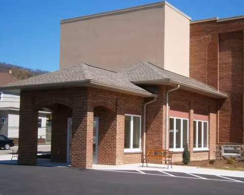 Brick building exterior with a covered entrance and pathway in front of a senior living facility.