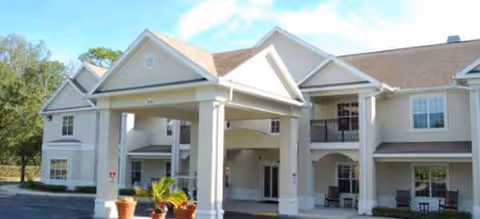 Exterior view of Brookdale Wekiwa Springs facility entrance with a covered porte-cochere and potted plants.