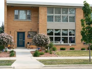 A brick building facade of Hawthorn Manor Inc with large front windows and landscaped walkway.