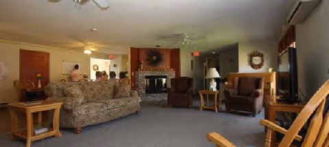 Cozy lounge in a senior living facility with sofas, chairs, and a fireplace.