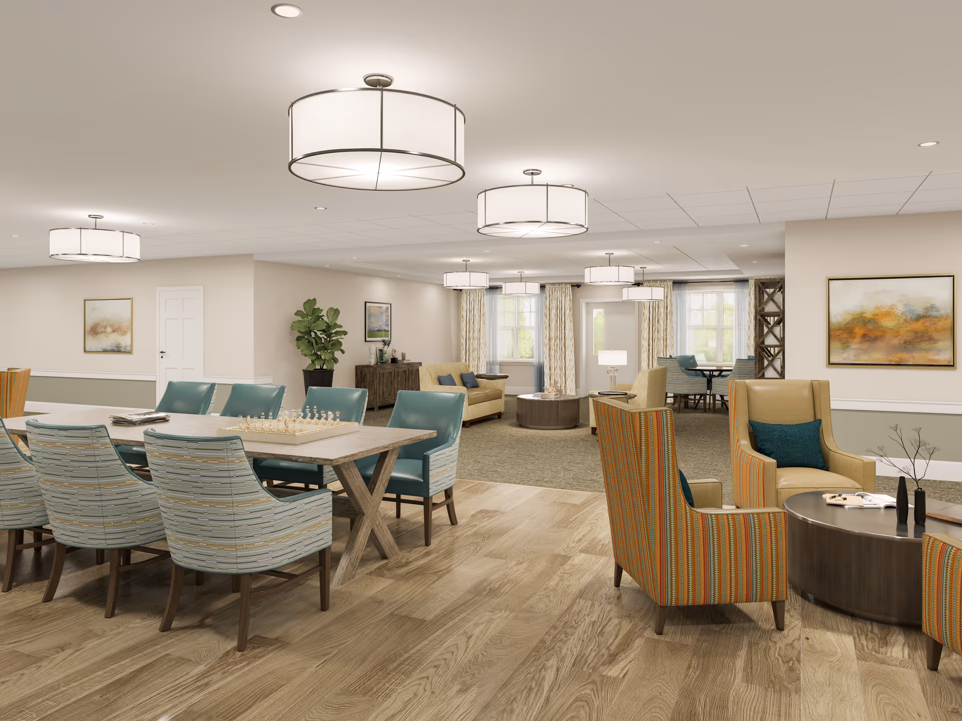 A spacious and well-lit common area in a senior living facility featuring multiple seating arrangements. There is a long table with chairs and a chessboard, several armchairs with cushions around a round coffee table, and sofas near the windows with curtains. The room has wooden flooring, neutral-colored walls with framed artwork, and modern ceiling lights.