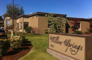 Exterior view of Willow Springs Care facility with a sign and landscaped front yard
