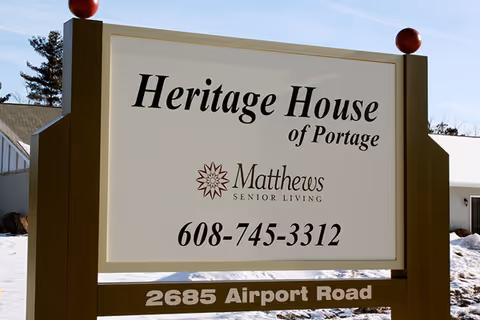 A large outdoor sign reading "Heritage House of Portage" with the Matthews Senior Living logo, phone number, and address.