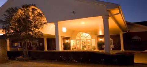 Night exterior view of Morada Lawton facility entrance with lit doorway and columns.