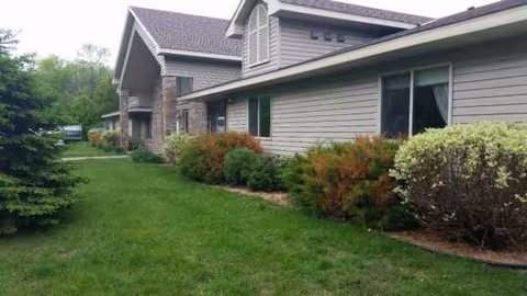 Exterior view of a senior living facility with manicured lawn and shrubs.