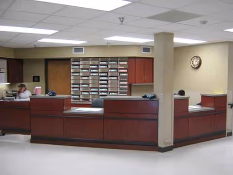 Curved reception desk in a nursing home lobby with staff and organized mail cubbies.