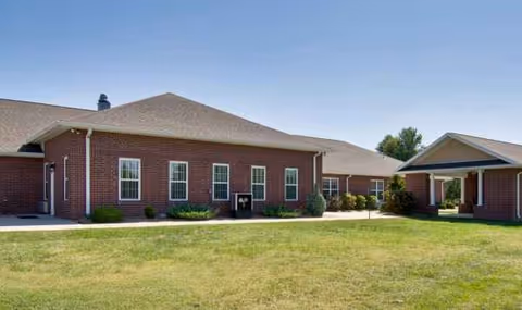 Brick senior living building with manicured lawn and covered entrance.