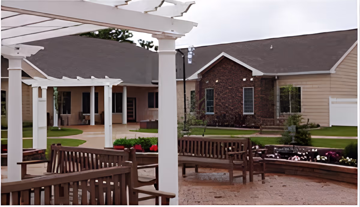 Outdoor courtyard with pergolas, wooden benches, flower beds, and the building facade in the background.
