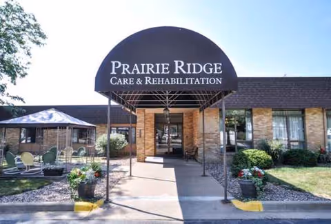 Exterior view of Prairie Ridge facility entrance with curved sign and outdoor seating.
