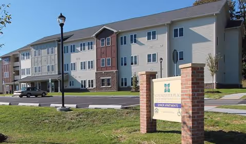 Exterior view of Ware Presbyterian Village building with lawn, sign, and street parking.