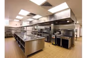 Commercial kitchen in a senior living facility with stainless steel prep tables and ovens.